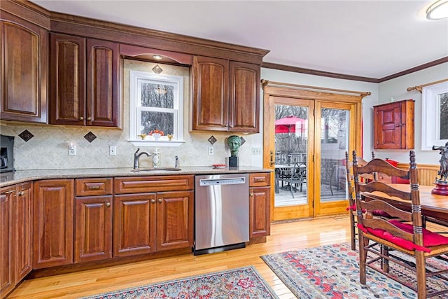 kitchen with light wood finished floors, ornamental molding, light stone countertops, stainless steel dishwasher, and a sink