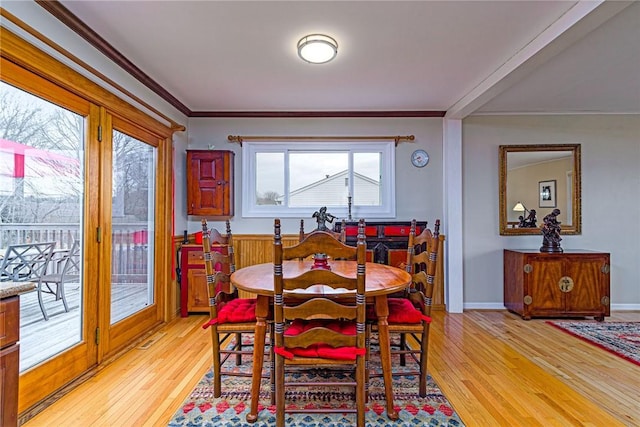 dining area with baseboards, light wood-type flooring, and crown molding