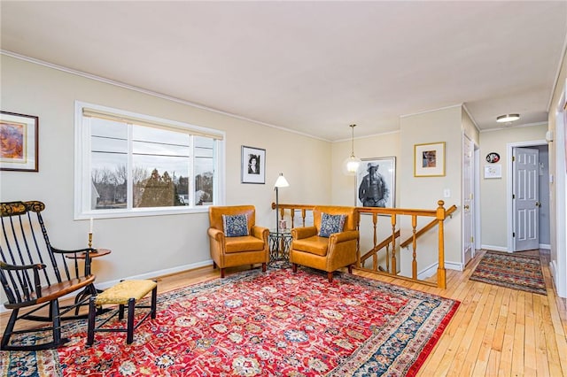 living area with light wood-type flooring, baseboards, crown molding, and an upstairs landing