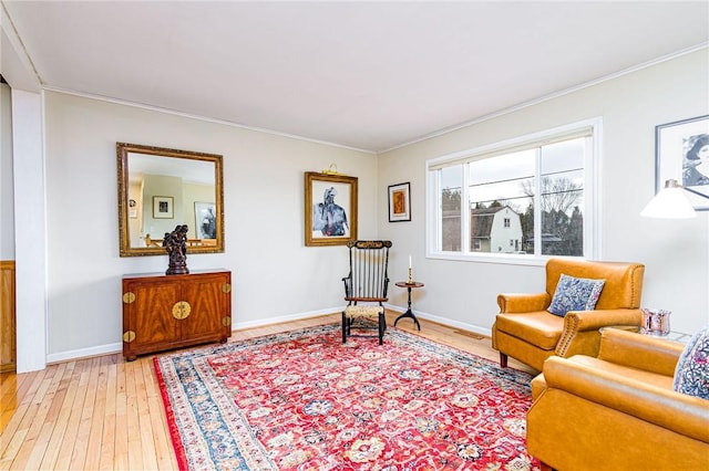 sitting room featuring light wood-style floors, baseboards, and crown molding