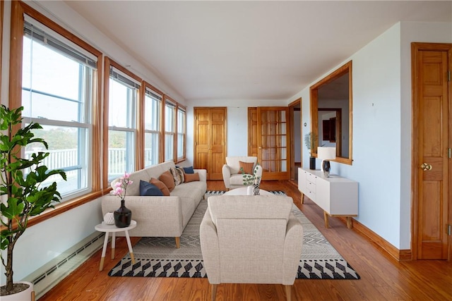 living room featuring a baseboard radiator, baseboards, and wood finished floors