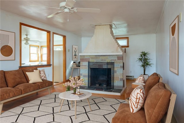 living area with a baseboard heating unit, wood finished floors, ornamental molding, and a fireplace