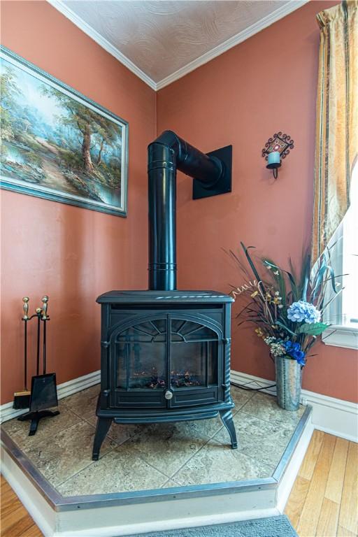 details with a wood stove, baseboards, crown molding, and wood finished floors