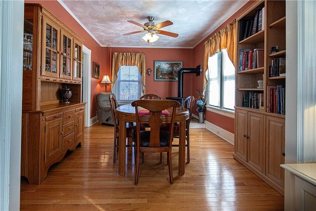 dining room with light wood-style flooring, ornamental molding, a ceiling fan, a textured ceiling, and baseboards