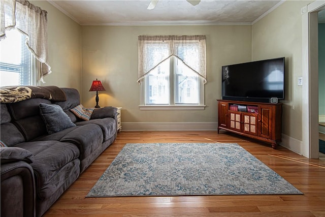 living area featuring crown molding, baseboards, and wood finished floors