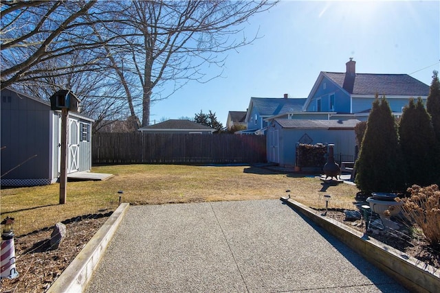 view of yard with a fenced backyard, an outdoor structure, a patio, and a storage unit