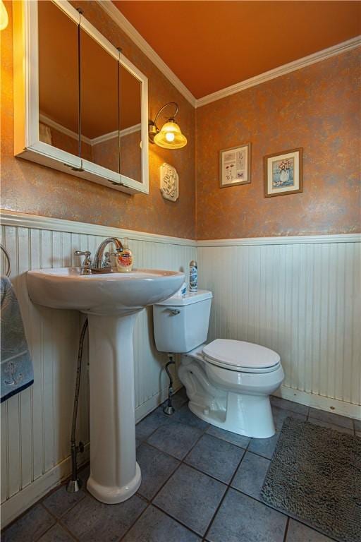 bathroom featuring toilet, a wainscoted wall, ornamental molding, and tile patterned floors