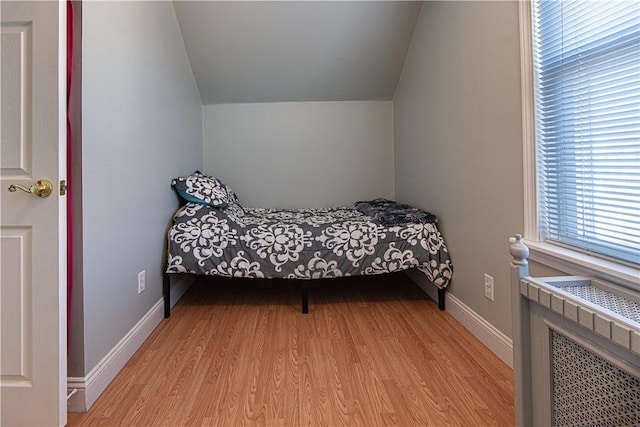 bedroom featuring light wood-style flooring, baseboards, and vaulted ceiling