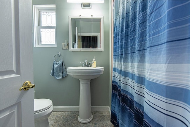 bathroom with a shower with shower curtain, toilet, a sink, tile patterned flooring, and baseboards