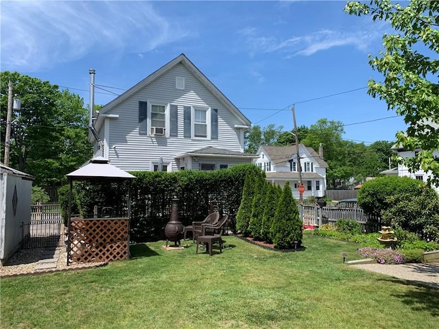 rear view of property featuring fence, a gazebo, and a lawn