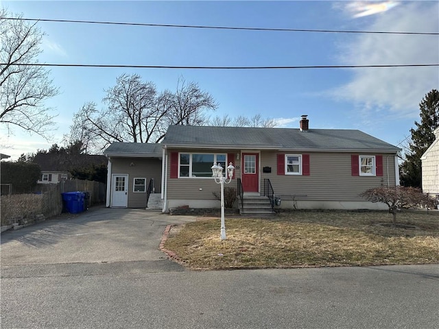 single story home featuring entry steps, a chimney, fence, and aphalt driveway