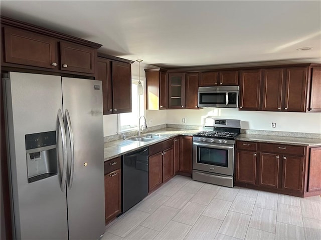 kitchen featuring dark brown cabinetry, glass insert cabinets, stainless steel appliances, pendant lighting, and a sink