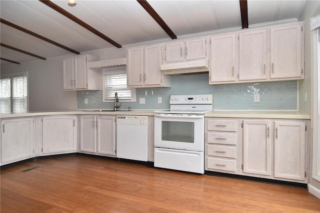 kitchen with white appliances, wood finished floors, a sink, light countertops, and beam ceiling