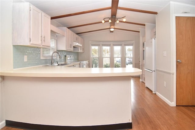 kitchen with white appliances, tasteful backsplash, lofted ceiling with beams, light countertops, and a sink