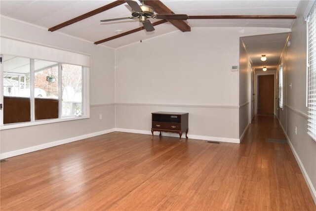 unfurnished room featuring visible vents, lofted ceiling with beams, ceiling fan, wood finished floors, and baseboards