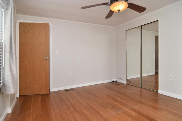 unfurnished bedroom with ornamental molding, visible vents, ceiling fan, and wood finished floors