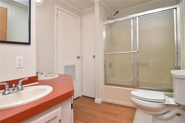 bathroom featuring enclosed tub / shower combo, toilet, wood finished floors, vanity, and visible vents