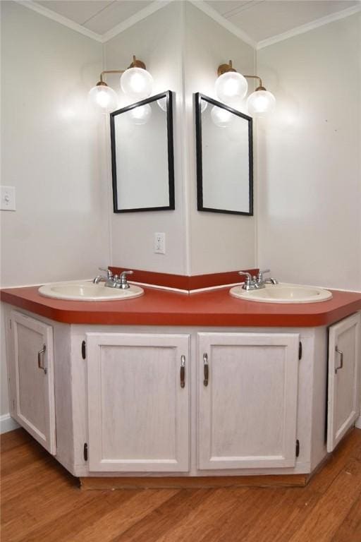 bathroom with ornamental molding, wood finished floors, a sink, and double vanity