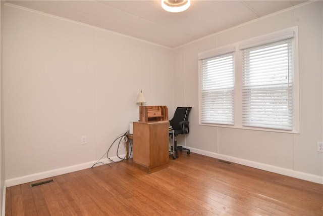 unfurnished office featuring ornamental molding, visible vents, baseboards, and wood finished floors