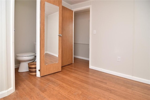 bathroom with toilet, baseboards, and wood finished floors