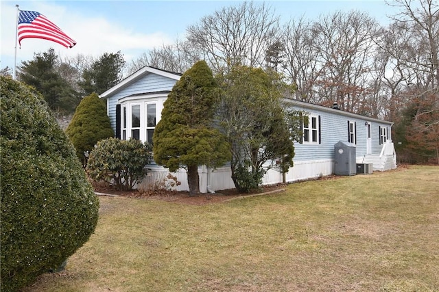 view of side of property with a lawn and central AC