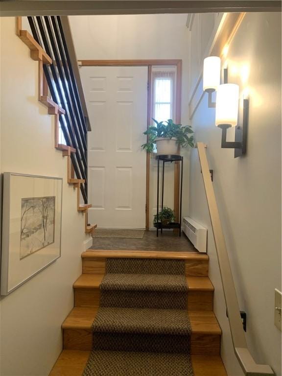 staircase with baseboard heating and wood finished floors