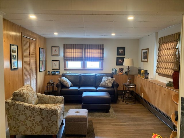 living area with a baseboard radiator, wooden walls, recessed lighting, and wood finished floors