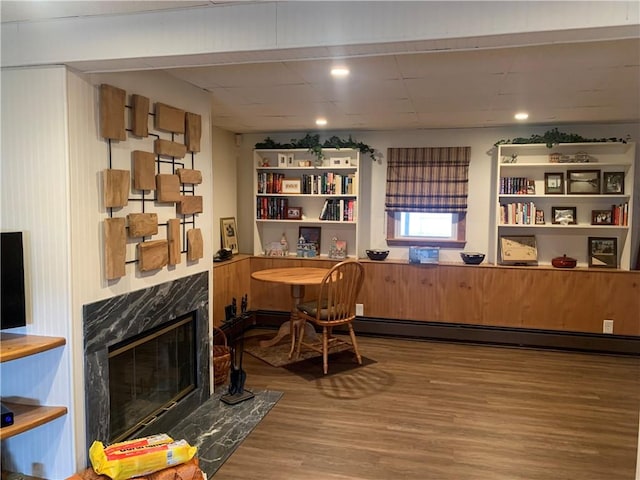 home office with a baseboard heating unit, a fireplace, and wood finished floors