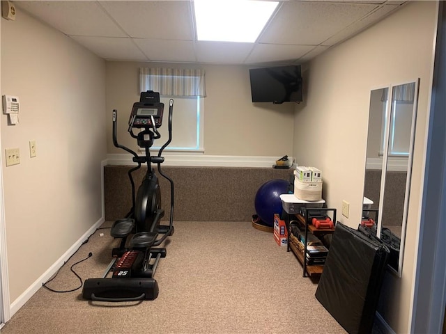 workout room featuring a paneled ceiling, carpet flooring, and baseboards