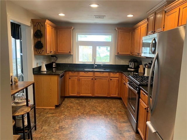 kitchen featuring dark countertops, visible vents, stainless steel appliances, and a sink