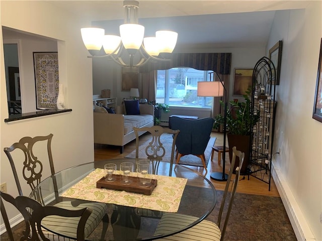 dining area with a chandelier, a baseboard radiator, baseboards, and wood finished floors