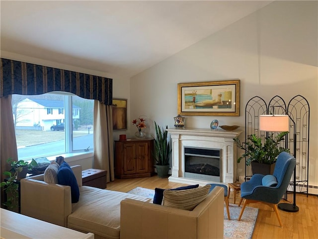 living area featuring light wood-style floors, high vaulted ceiling, and a glass covered fireplace