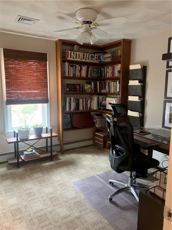 office space featuring baseboard heating, visible vents, and a ceiling fan