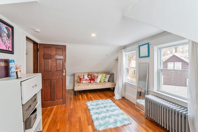 bedroom with radiator, light wood finished floors, and lofted ceiling