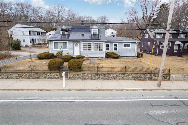 view of front facade with a fenced front yard, a residential view, and roof mounted solar panels