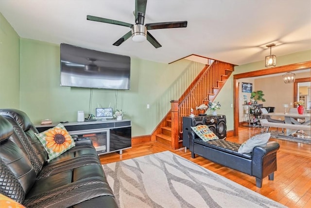 living room with wood-type flooring, stairway, and ceiling fan with notable chandelier