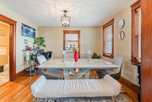 dining area with light wood-style flooring, baseboards, and a notable chandelier