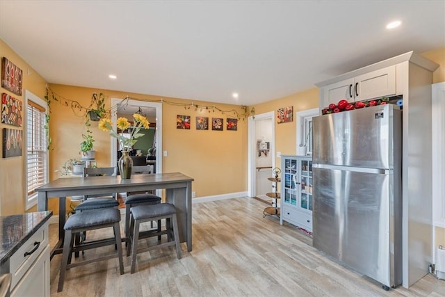 kitchen featuring white cabinets, light wood finished floors, freestanding refrigerator, and recessed lighting