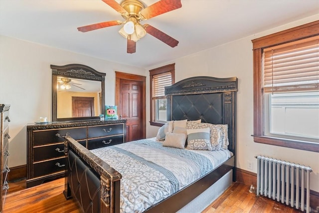 bedroom featuring a ceiling fan, baseboards, radiator heating unit, and wood finished floors