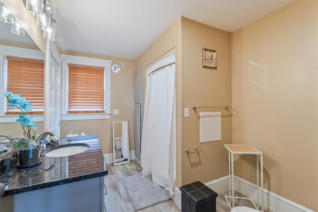 full bathroom with a shower with curtain, wood finished floors, vanity, and baseboards