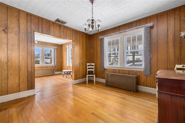 dining space featuring a chandelier, visible vents, light wood finished floors, and radiator heating unit