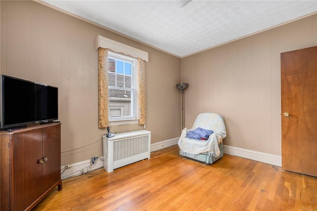 unfurnished room featuring hardwood / wood-style flooring, radiator heating unit, and baseboards