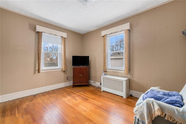 bedroom with light wood-style floors, radiator, multiple windows, and baseboards