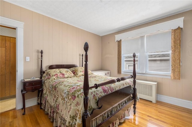 bedroom with radiator, baseboards, and wood finished floors