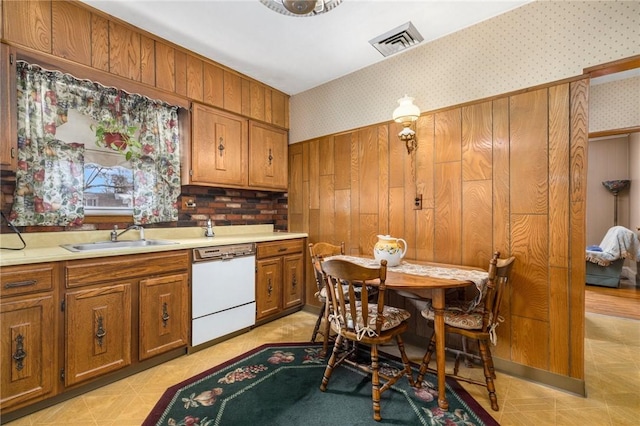 kitchen featuring visible vents, dishwasher, a sink, and wallpapered walls