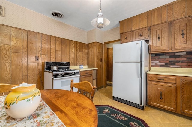 kitchen featuring white appliances, visible vents, brown cabinetry, and wallpapered walls