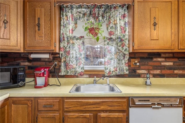 kitchen with light countertops, brown cabinetry, a sink, black microwave, and dishwasher