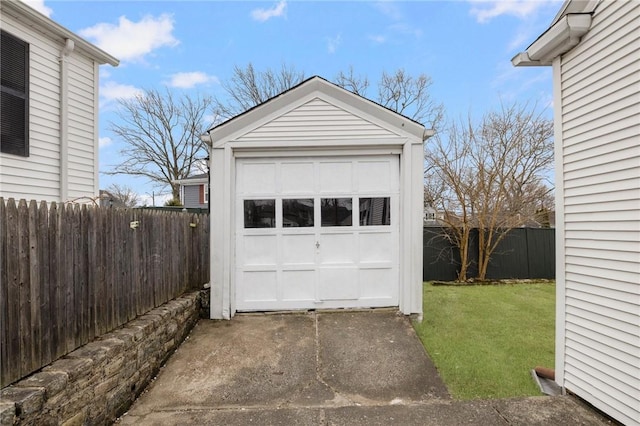 detached garage featuring fence and concrete driveway