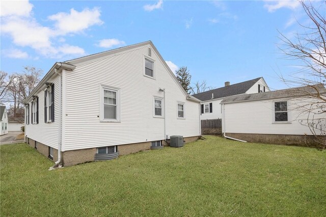 rear view of property with central air condition unit and a yard