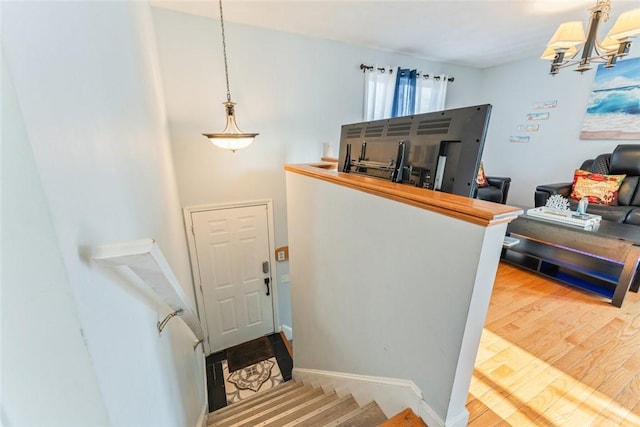 staircase with a notable chandelier, baseboards, and wood finished floors